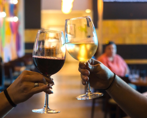 two hands tapping two wine glasses together - cheers!