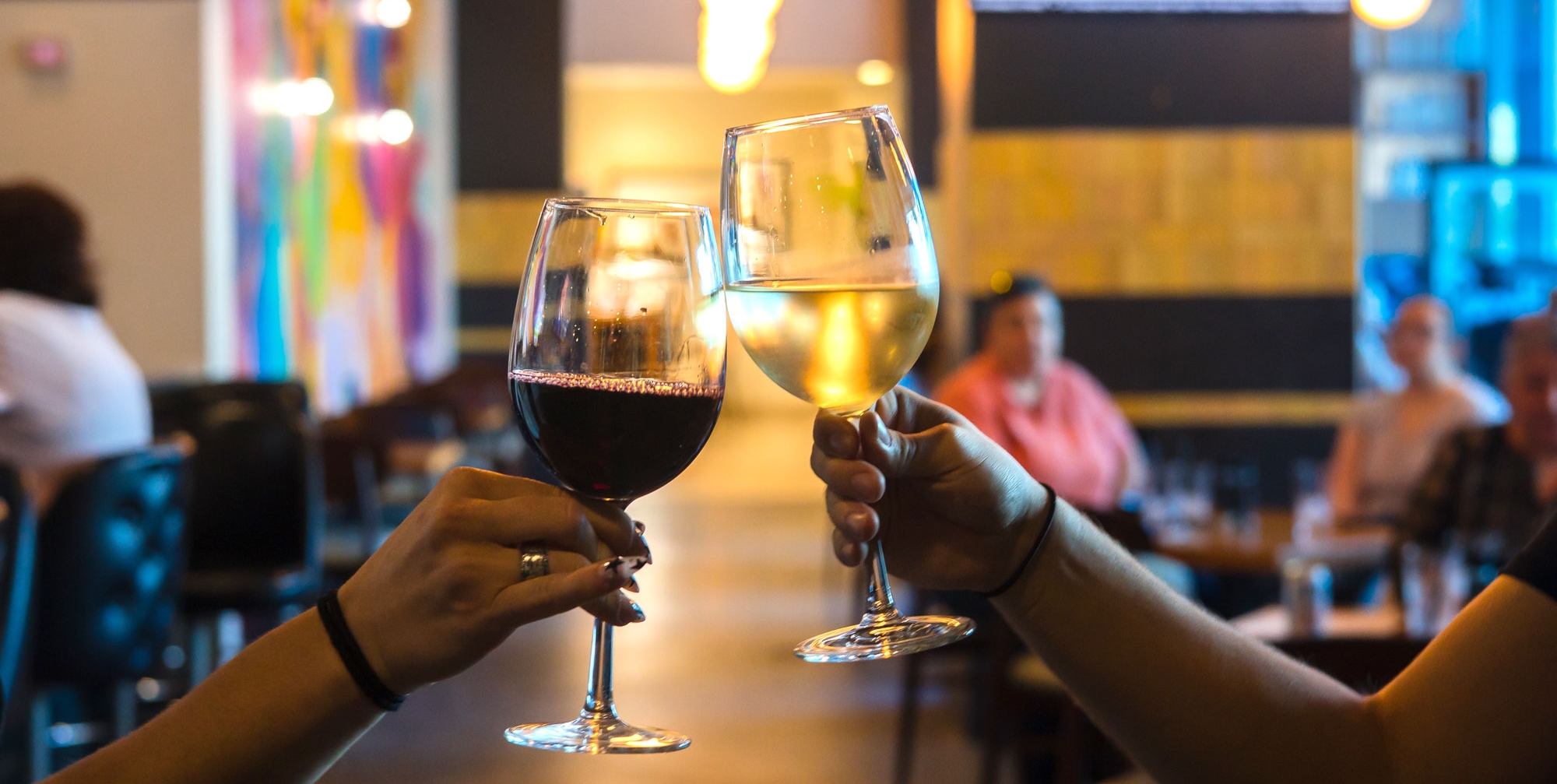 two hands tapping two wine glasses together - cheers!